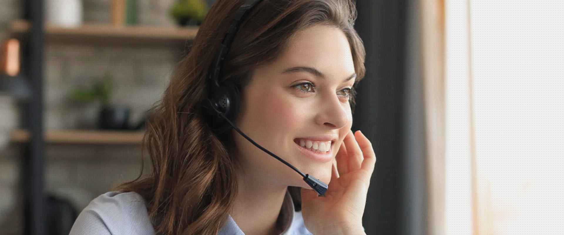 Frau mit Headset lächelt während eines Kundengesprächs am Telefon.
